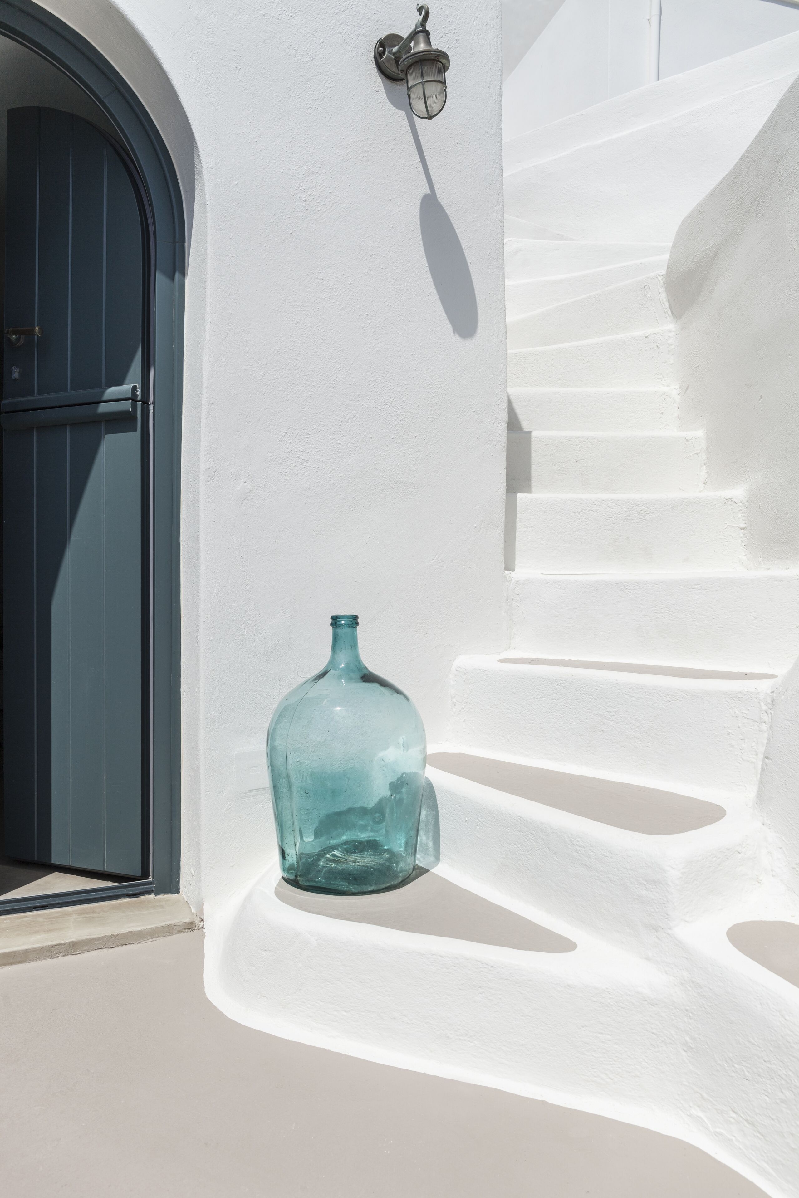 Un escalier blanc avec une bouteille en verre bleue posée sur les marches.
