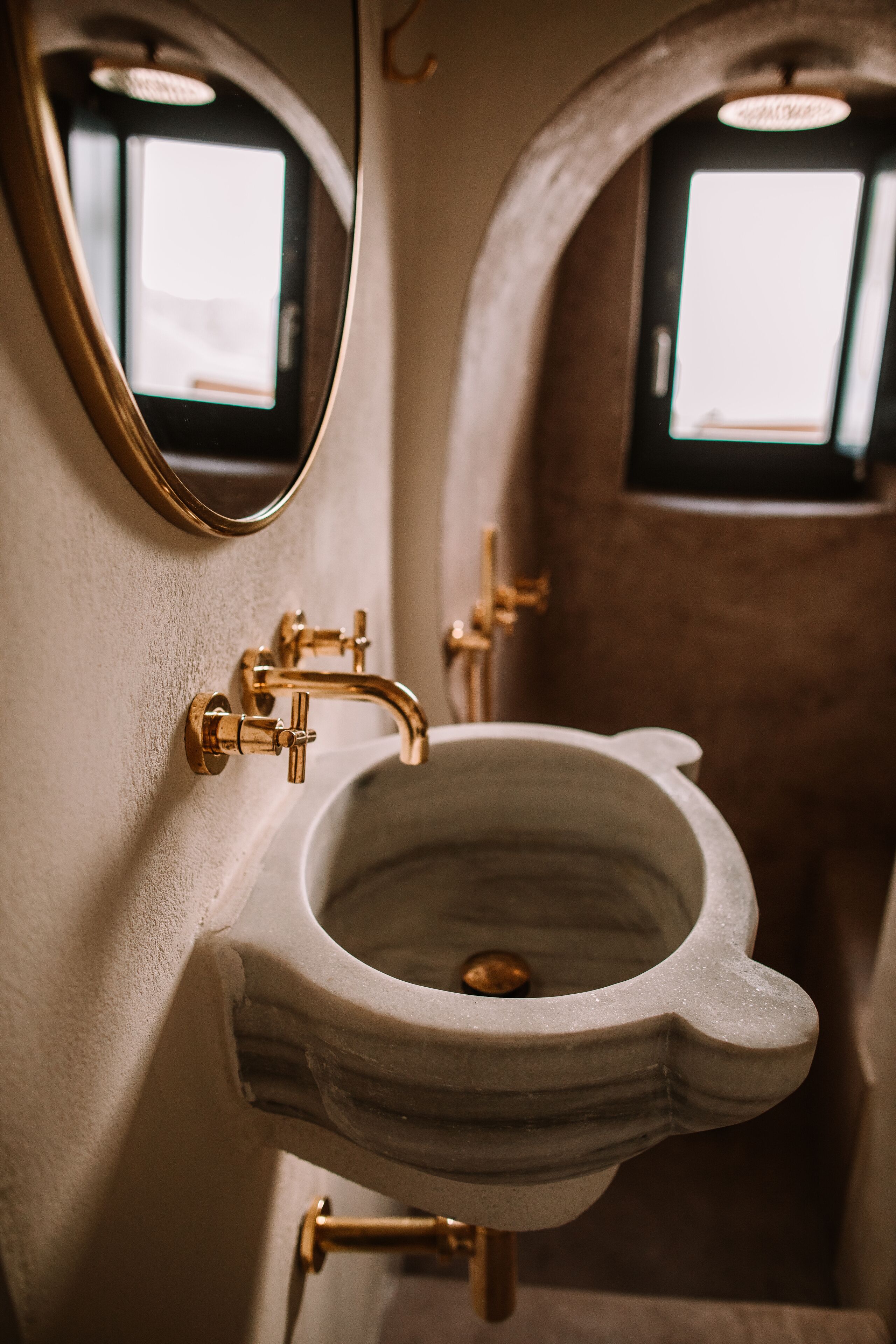 A bathroom with a unique toilet and sink design, featuring a marble sink and gold fixtures.