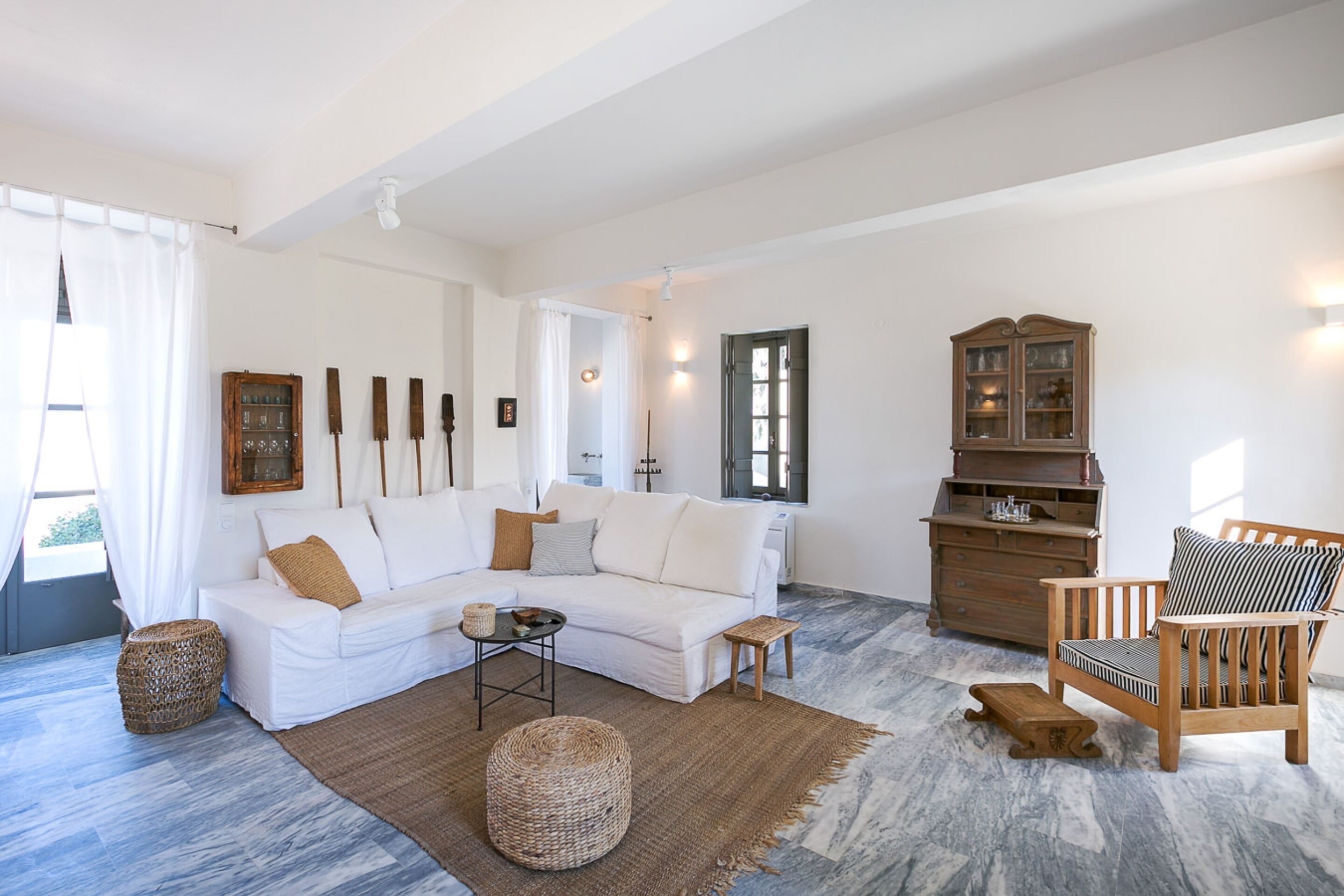 A living room with a white sofa, a wooden chair, a cabinet, and a coffee table.
