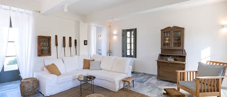 A living room with a white sofa, a wooden chair, a cabinet, and a coffee table.