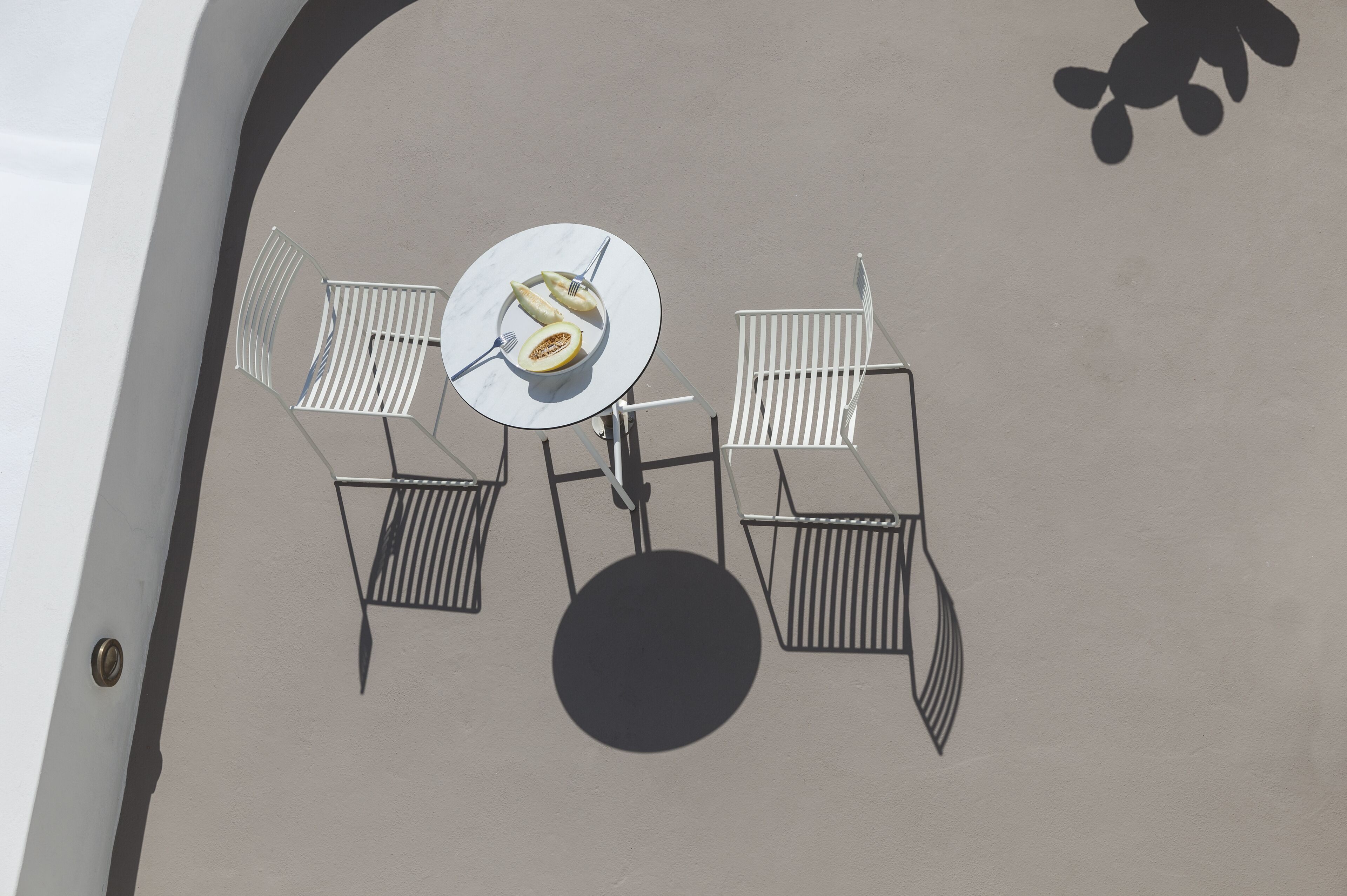 A dining area with a round table, four chairs, and a central plate with food.