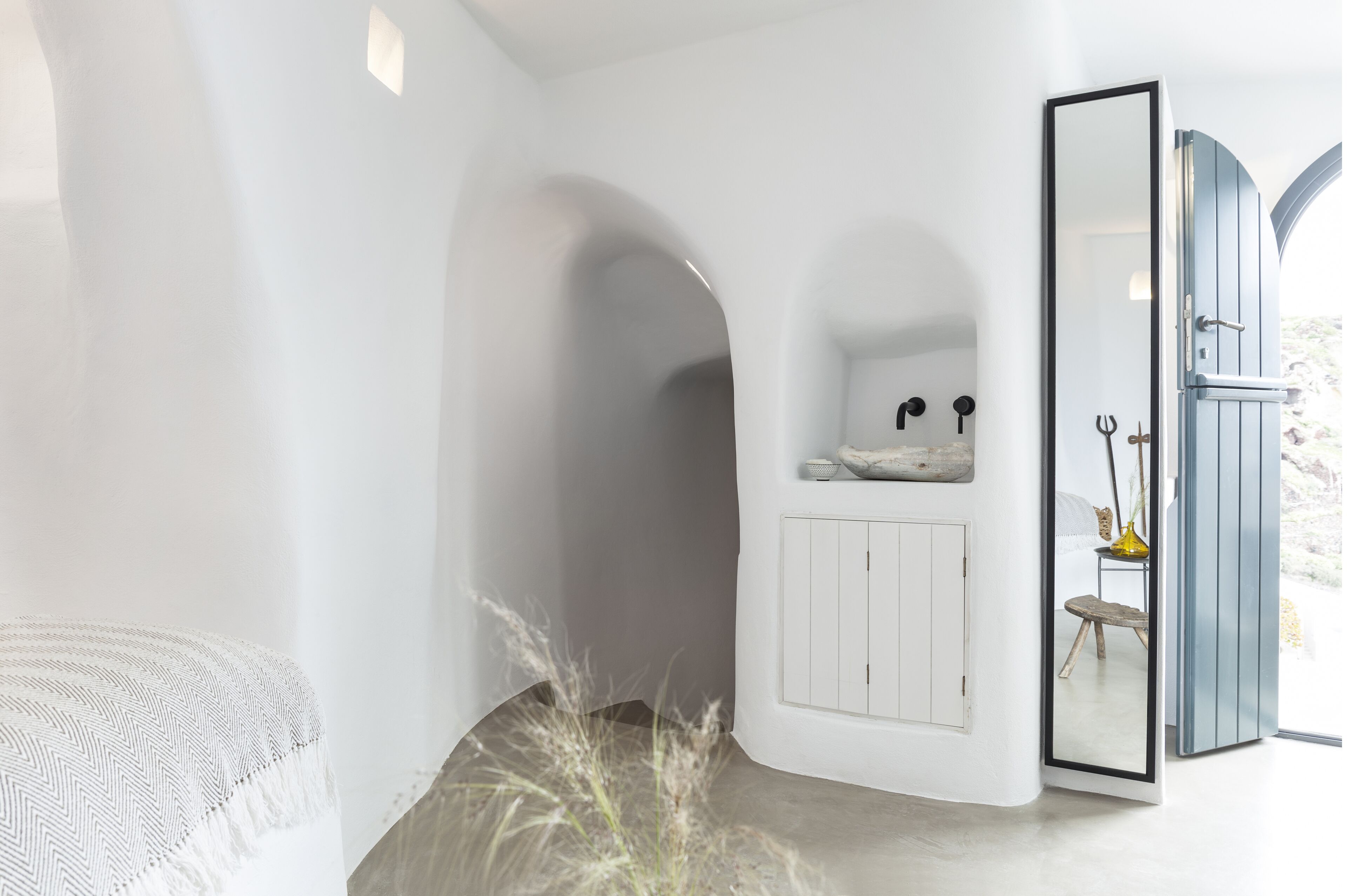 Une salle de bain moderne avec un meuble-lavabo blanc, un miroir et une porte donnant sur une autre pièce.