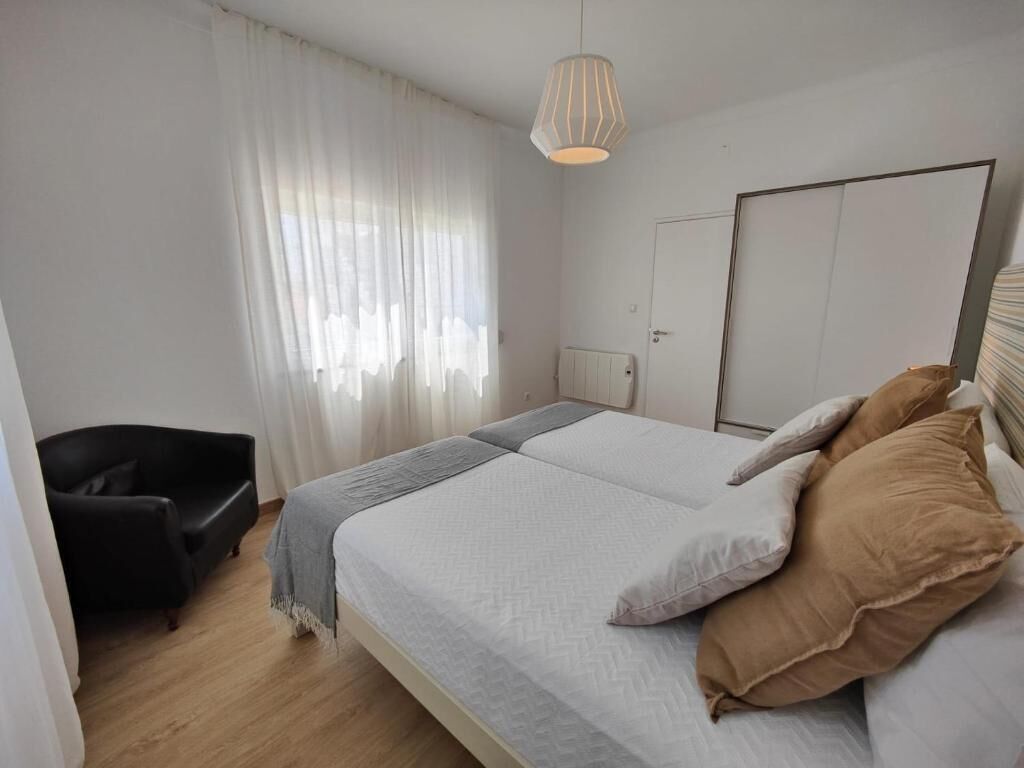 A bedroom with a bed, a chair, a radiator, and a wardrobe.