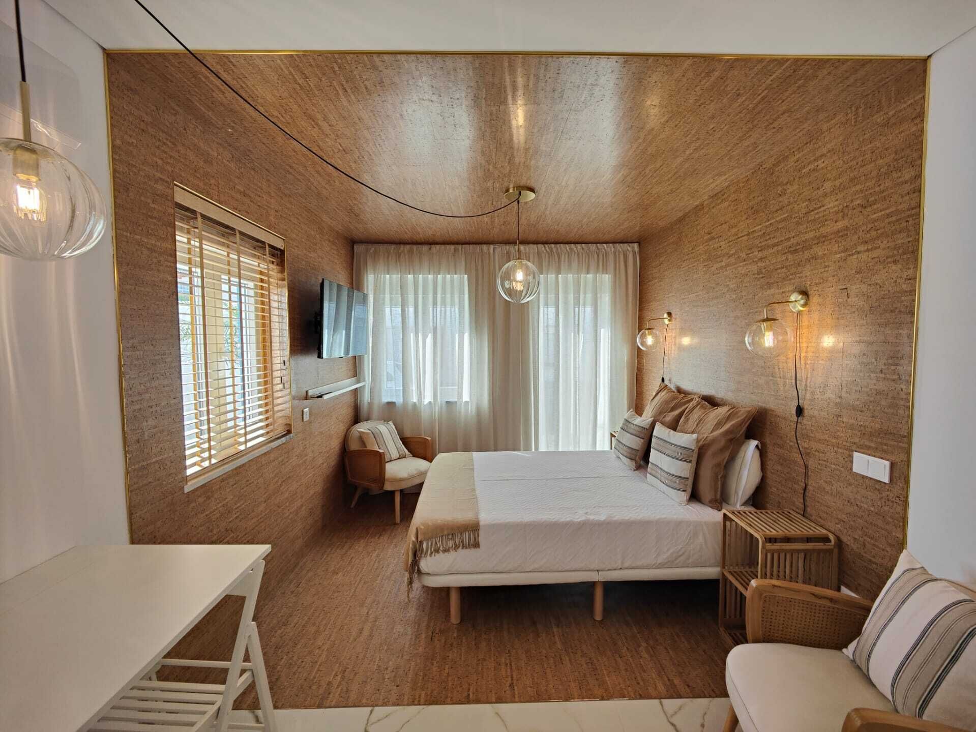 Un dormitorio moderno con una pared de madera, una cama con almohadas, una silla, un televisor y una mesita de noche.