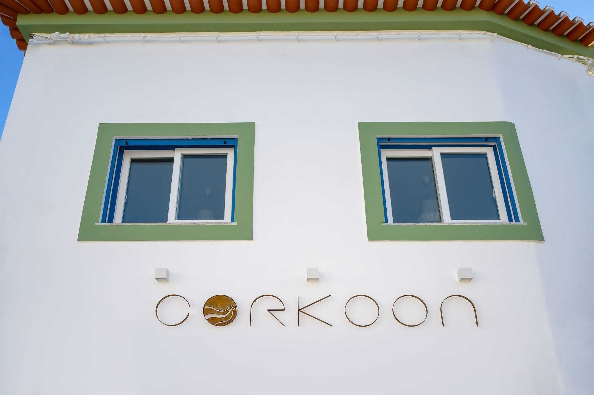 A building with two windows and a sign that reads "Corkoon".