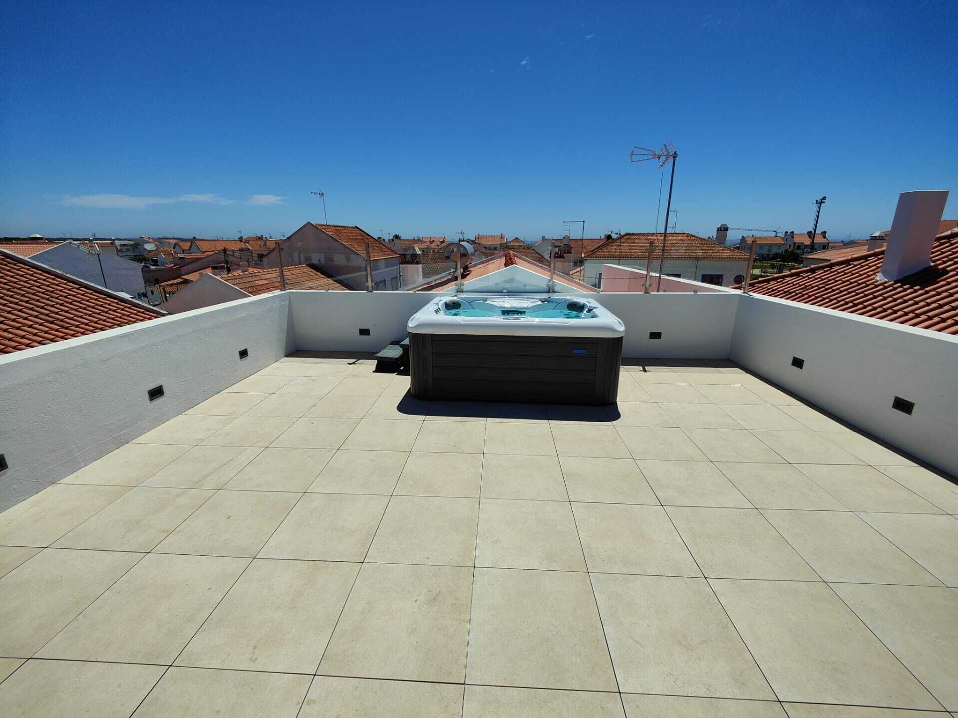 Eine Dachterrasse mit Whirlpool, gefliestem Boden und freiem Blick auf die umliegende Gegend.