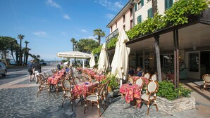 An outdoor café with tables and chairs, a sign for 'Caffè Grande Italia,' and a stone-paved area. - Casa Emma with Pool (Sirmione)