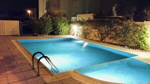 A rectangular swimming pool with a ladder on one side, surrounded by a tiled deck and a low wall with greenery. - Casa Emma with Pool (Sirmione)