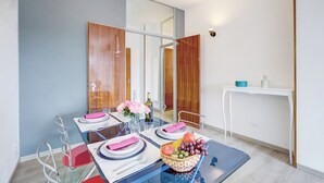 A modern dining area with a glass table, metal chairs, and a white console table with a vase of flowers. - Appartamento di Tommaso (Desenzano del Garda)