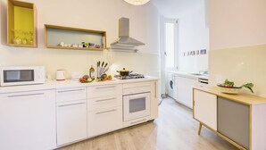 A modern kitchen with white cabinetry, a microwave, a stove, and a sink. - Appartamento di Tommaso (Desenzano del Garda)