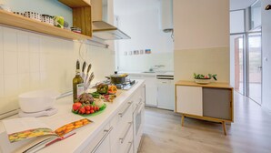 A modern kitchen with white cabinets, a wooden countertop, and a small cabinet with a plant. - Appartamento di Tommaso (Desenzano del Garda)