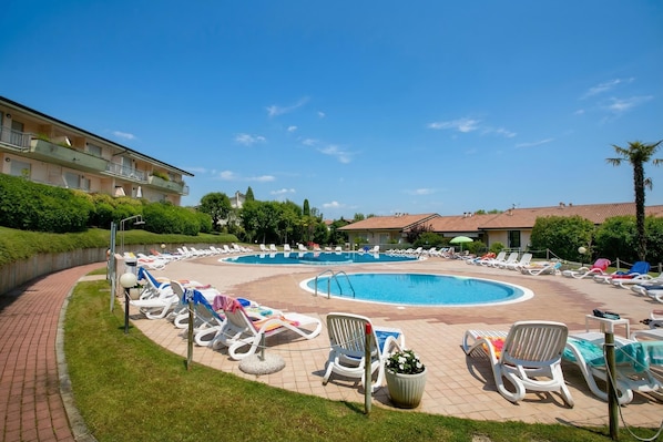 A swimming pool with lounge chairs and a building in the background.