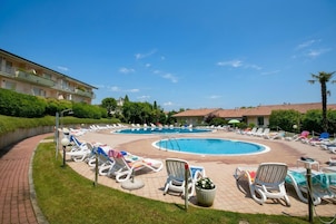 En swimmingpool med solstolar och en byggnad i bakgrunden.