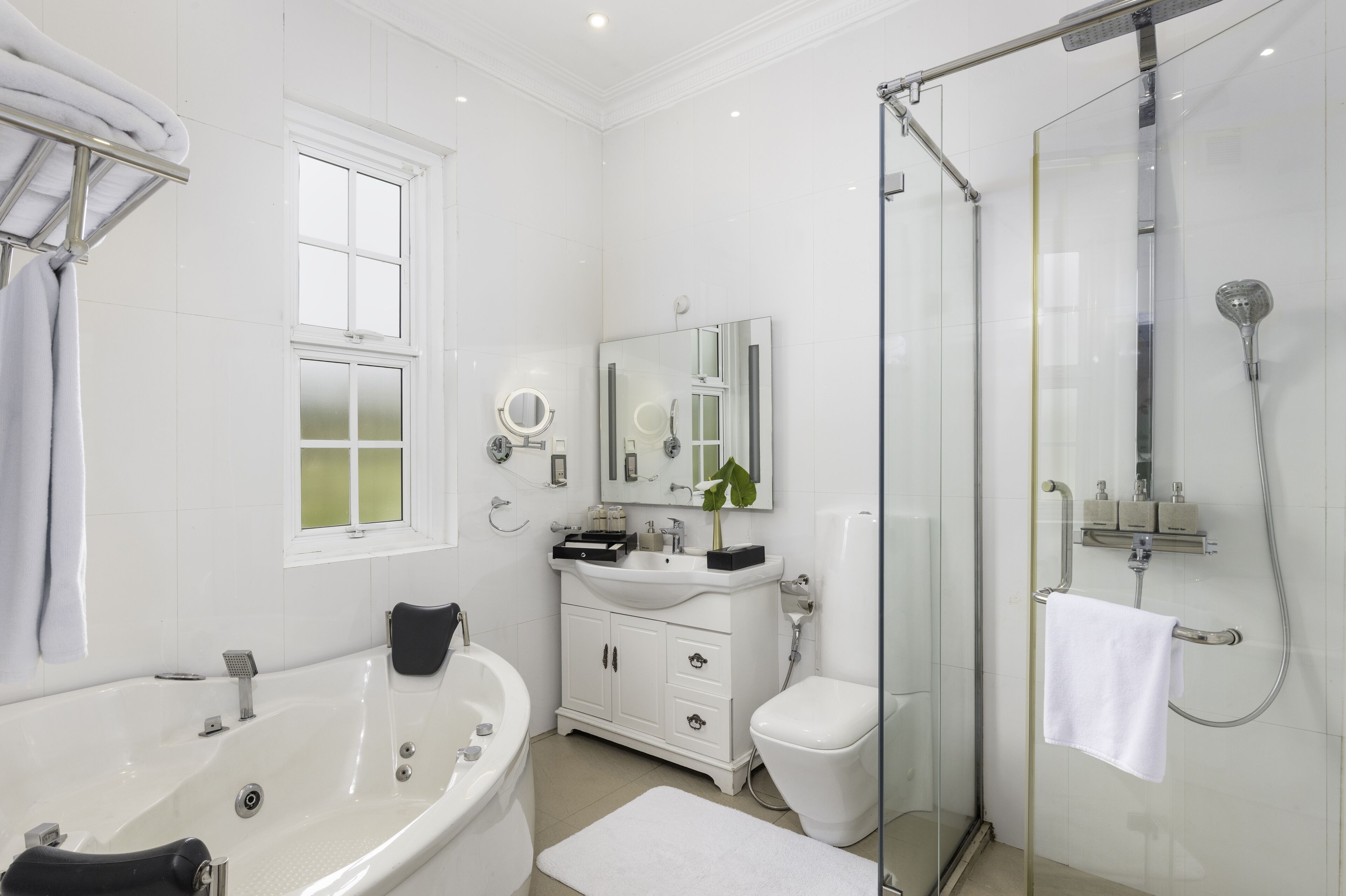 Une salle de bain moderne comprenant une baignoire, une douche à parois de verre, un meuble-lavabo avec un miroir et des toilettes.