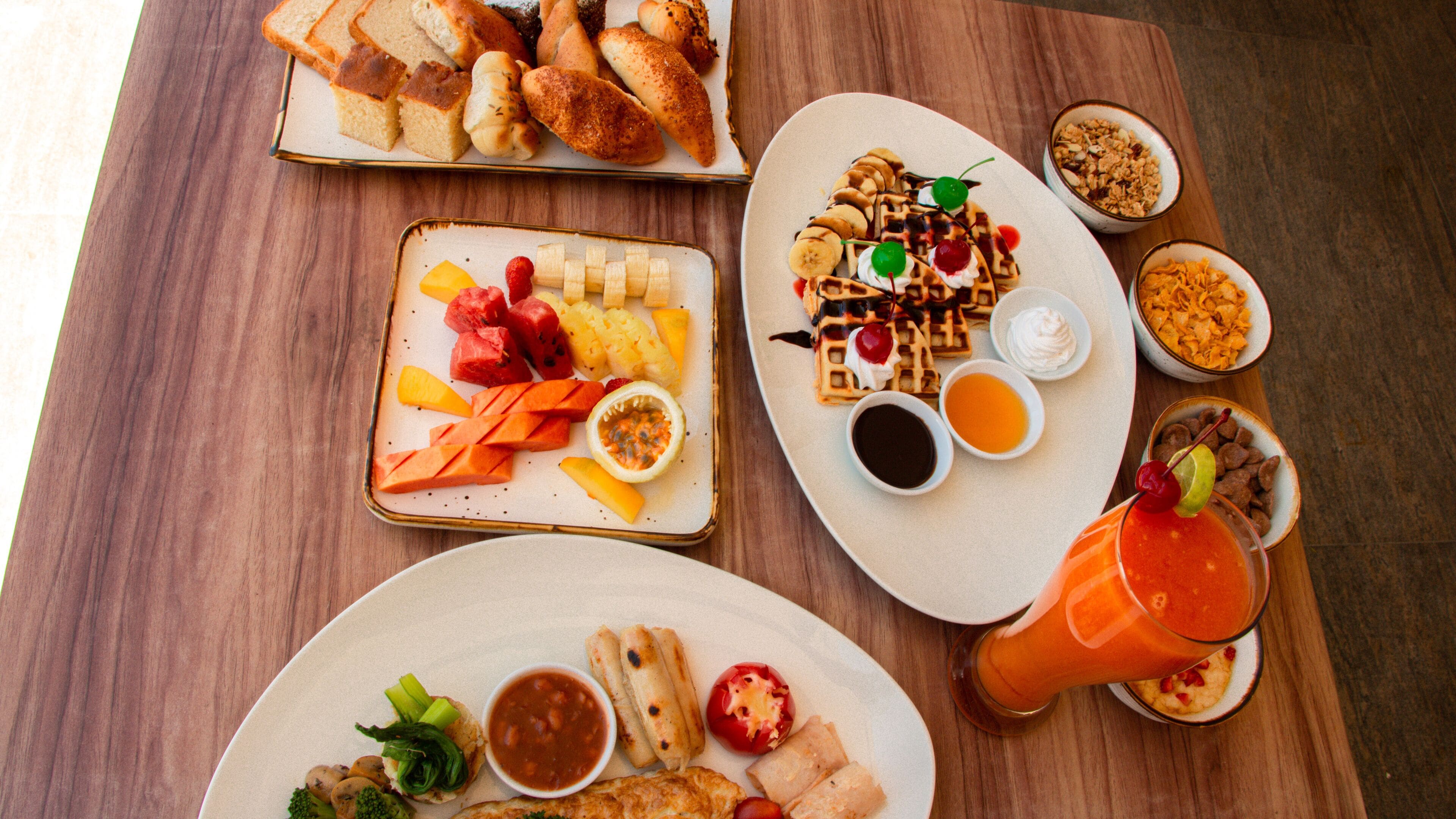 Une table garnie de divers plats, notamment du pain, des gaufres et des fruits.