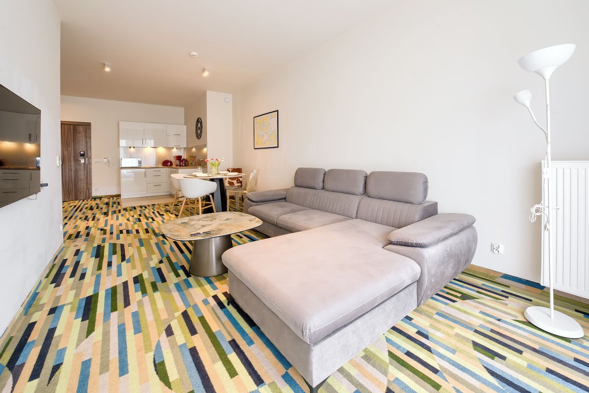 A modern living room with a grey sectional sofa, a coffee table, and a patterned rug.