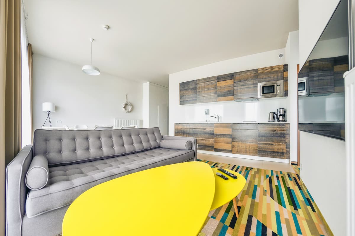 A modern living room with a grey sofa, a yellow coffee table, and a patterned rug.