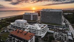Un complejo hotelero moderno con varias edificaciones, incluyendo una estructura curva destacada y un edificio rectangular alto.