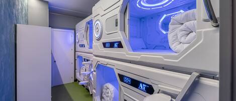 Una fila de habitaciones modernas de estilo cápsula, en color blanco, con iluminación integrada y pantallas digitales.
