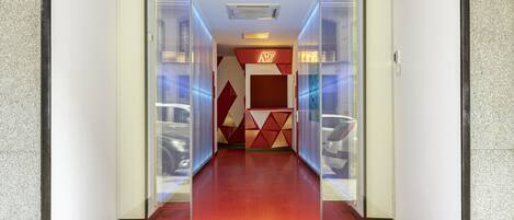 An interior corridor leading to a room with a red carpet and a sign reading "Art Seven Hostel".