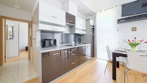 Cocina moderna con horno empotrado, microondas y fregadero. Hay una zona de comedor con mesa y sillas.