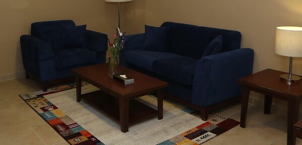 A living room with two blue sofas, a coffee table, a side table with a lamp, and a patterned rug.