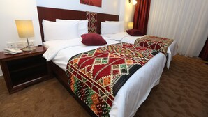A hotel room with a large bed, two bedside tables, a nightstand, a telephone, and a painting on the wall. - Hotel Name Samawer by Wynndham Amman Hotel (Amman)