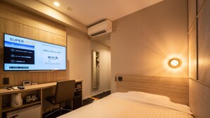 A hotel room with a bed, a desk, a chair, a TV displaying hotel information, and a wall-mounted air conditioner. - Super Hotel Matsumoto Tennen Onsen (Matsumoto)