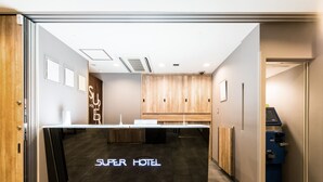 A reception desk with a sign reading "Super Hotel" in a modern lobby with wooden paneling and a tiled floor. - Super Hotel Matsumoto Tennen Onsen (Matsumoto)