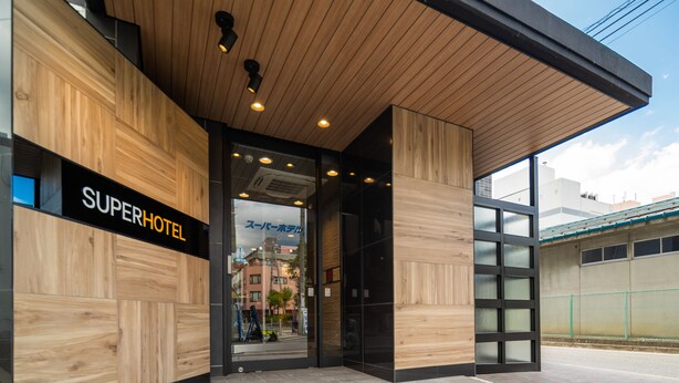 A modern hotel entrance with a wooden facade and glass doors. - Super Hotel Matsumoto Tennen Onsen (Matsumoto)