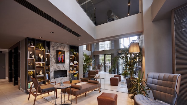 A spacious living area with a fireplace, comfortable seating, and a high ceiling with skylights. - Avantgarde Urban Şişli (Istanbul)