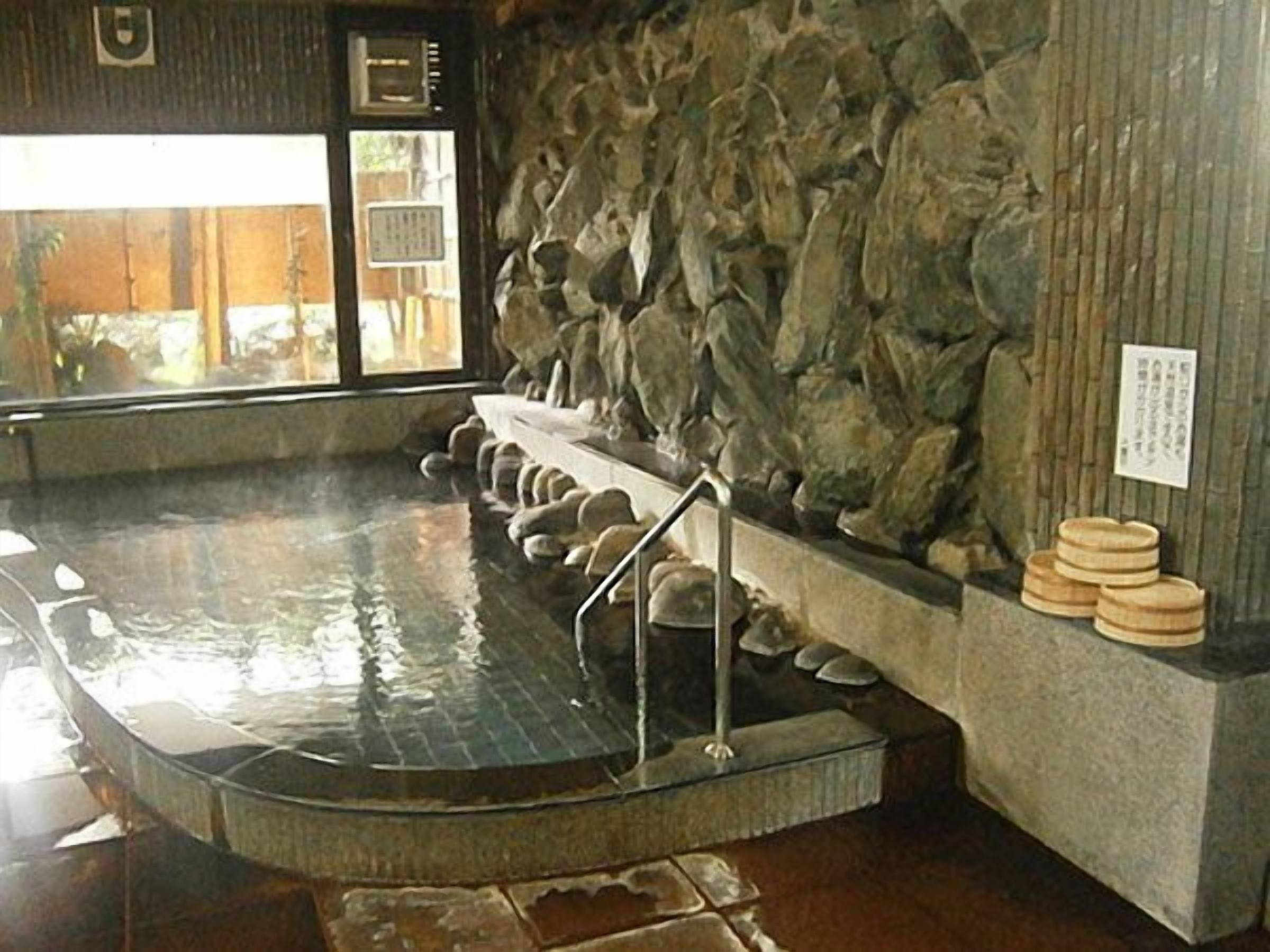 A stone wall with a hot spring bath, a wooden bench, and a stone platform.