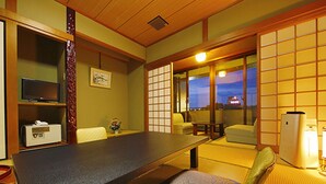 A traditional Japanese-style room with tatami flooring, a low table, a sofa, and sliding doors leading to a balcony. - Daikans (Chikushino)