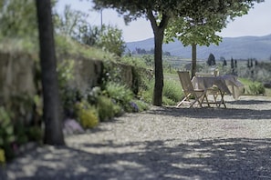 A gravel path leading to a table set outdoors with a view of hills. - Luxury Chianti in Olive (Greve in Chianti)
