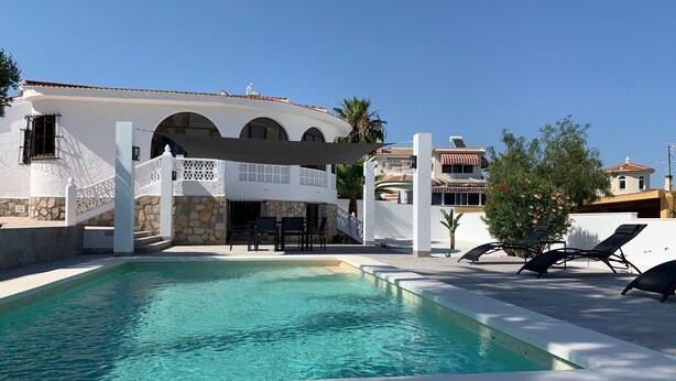 A swimming pool with a white building in the background, stone steps, and outdoor seating. - CASA CARLOS - Private Villa Detached with Pool (Cdad. Quesada)