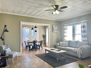 A spacious living room with a ceiling fan, a dining area with a table and chairs, a sofa, and a coffee table. - Vidalia Sweet Onion Home in Downtown Lyons, with King Bed-Travel Workers Welcome (Lyons)