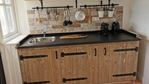 A kitchen with wooden cabinets, a black countertop, and a hanging utensil rack.
