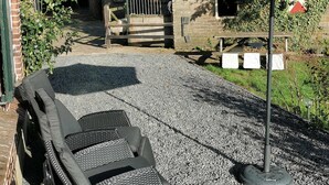 An outdoor seating area with a table and chairs, a covered picnic table, and a small building with a sloped roof.