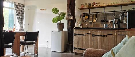 A modern kitchen with wooden cabinets, a white refrigerator, and a variety of kitchen utensils hanging above the counter.