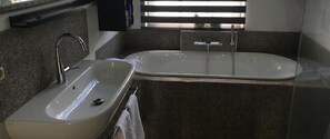 Een badkamer met een wit wastafelmeubel, een spiegel en een bad.
