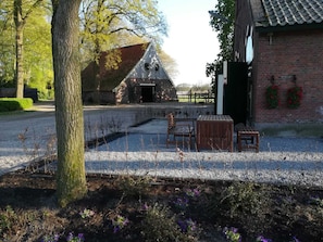 A rustic barn with a gravel driveway, a wooden bench, and a table.