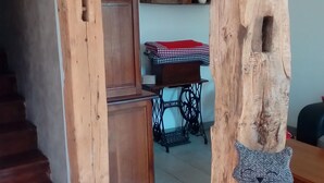 A rustic interior with a wooden staircase, a sewing machine, and a table with a checkered tablecloth.
