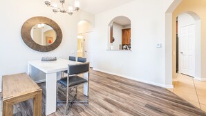 A dining area with a white table, black chairs, a wooden side table, and a chandelier. - Modern Vista Cay nr pool•Walk to OCCC close iDrive (Orlando)