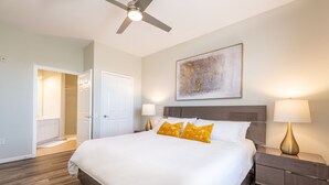 A hotel room with a large bed, two bedside lamps, a ceiling fan, and a painting on the wall. - Modern Vista Cay nr pool•Walk to OCCC close iDrive (Orlando)