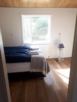 Un dormitorio con cama, ventana, radiador y lámpara.