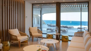 A modern lounge with wicker furniture, a white sofa, and a view of the ocean. - ROBINSON IERAPETRA (Ierapetra)