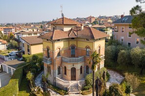 A multi-story building with a central courtyard, surrounded by a garden with palm trees and a stone pathway.
