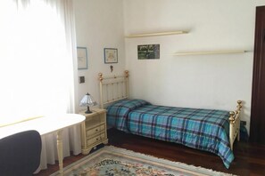 A bedroom with a bed, a desk, a chair, a lamp, and a rug.