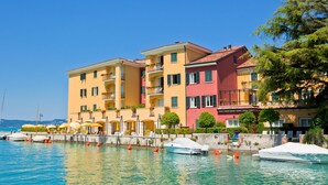 A waterfront hotel with multiple balconies, a pool area, and boats docked nearby. - Villa Barbara (Desenzano del Garda)