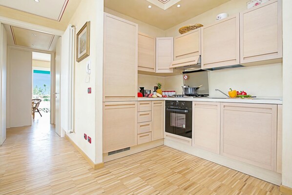 A kitchen with wooden cabinets, a stove, and a sink. - Casa Bel Tramonto (Sirmione)